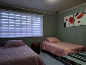 1 dormitorio con 2 camas y ventana en Casa completa para 6 personas centro Puerto Montt, 700 metros estatua enamorados, en Puerto Montt