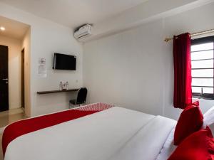 um quarto com uma cama branca e uma televisão em Super OYO Capital O 3463 Cimahi Guest House em Bandung