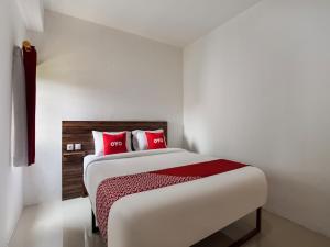 1 dormitorio con 1 cama grande con almohadas rojas en Super OYO Capital O 3463 Cimahi Guest House, en Bandung