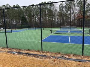 two tennis courts are seen through a fence at Deck, BBQ Grill, Backyard Fire Pit, Pool, Jacuzzi Tub, 65 inch TV in Douglasville