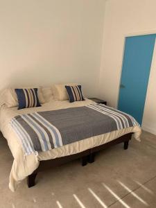 Cama en habitación con puerta azul en Casa Playera, en Puchuncaví