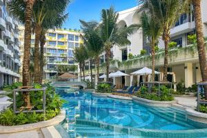a swimming pool with palm trees and buildings at La Green Hotel and Residence in Bang Tao Beach
