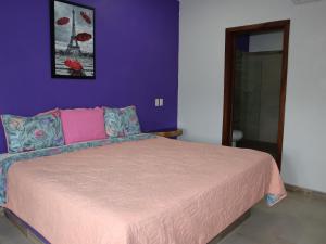 a bedroom with a bed with a purple wall at Playa Sayulita in Sayulita
