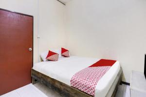 1 cama con almohadas rojas y blancas en una habitación en SPOT ON 91422 Ringin Pitu 2 Syariah en Jodoh
