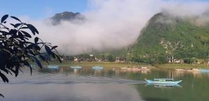 a group of boats on a river with a mountain at Diep Le Homestay in Phong Nha