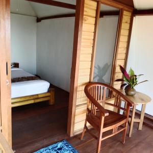 a room with a bed and a table and a chair at Bali jungle cabin in Jatiluwih
