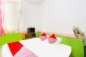 1 dormitorio con 2 camas y almohadas rojas y blancas en OYO 91344 Wr House Syariah Batam en Jodoh