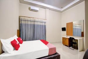 a bedroom with a bed and a desk in it at OYO 92065 Kos Flobamor in Kupang