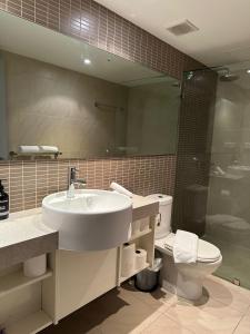 een badkamer met een wastafel, een toilet en een spiegel bij Pandanas Apt 5 15th fl Darwin CBD Harbor views in Darwin
