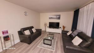een woonkamer met 2 leren stoelen en een televisie bij Home away from home - 6 bedroom fantastic bungalow in Winnipeg