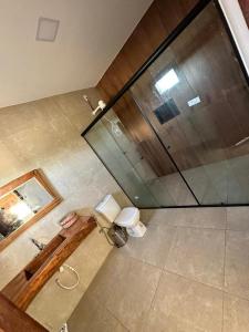 uma vista superior de uma casa de banho com um WC e uma parede de vidro em Pacas Suítes Casa & Chalés em Santo Amaro