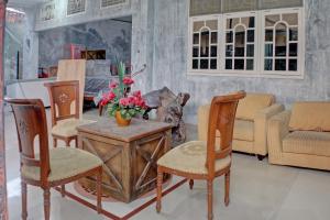 une chambre avec des chaises et une table fleurie. dans l'établissement SPOT ON 92834 Wisma Dira Tiara Syariah, à Lampung