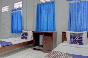 Cette chambre comprend 2 lits et des rideaux bleus. dans l'établissement SPOT ON 92834 Wisma Dira Tiara Syariah, à Lampung