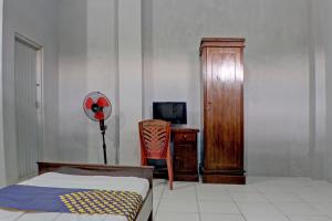 een slaapkamer met een bed, een kast en een stoel bij SPOT ON 92834 Wisma Dira Tiara Syariah in Lampung