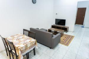 a living room with a couch and tables and a television at Tok Umi Guesthouse@AMJ Bakri in Muar
