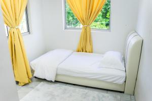 a bed with yellow curtains in a bedroom at Tok Umi Guesthouse@AMJ Bakri in Muar