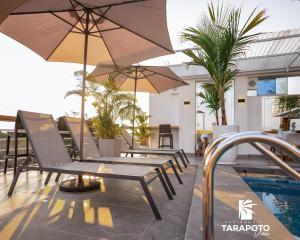 a patio with chairs and umbrellas next to a pool at Residencial Tarapoto View in Tarapoto
