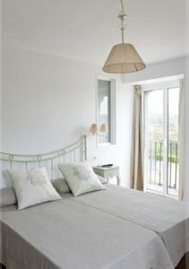 a white bedroom with a large bed and a window at Hostal Doña Blanca in Sigüenza