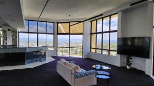sala de estar con sofá y TV y algunas ventanas en Surfers Hawaiian Holiday Apartments, en Gold Coast