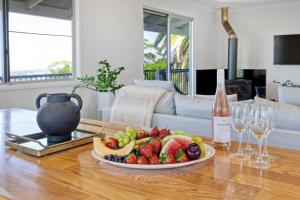a plate of fruit on a table with a bottle of wine at The Breezy Maple - Hinterland and range views in Mapleton in Mapleton