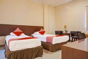 two beds in a room with chairs and a table at Collection O 91414 Hotel Marina Beach in Makassar