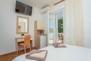 um quarto com uma cama, uma secretária e uma janela em Guest House Lovrić em Lumbarda