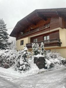 une maison avec des arbres enneigés devant elle dans l'établissement Haus Karin Mallnitz, à Mallnitz