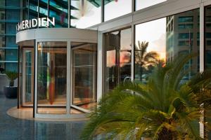 a large glass building with a sign on it at Le Royal Meridien Abu Dhabi in Abu Dhabi