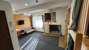 uma pequena sala de estar com um sofá e uma televisão em オレンジの風 em Imabari