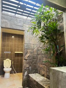 a bathroom with a toilet in a stone wall at เอนกายสบายรีสอร์ต in Ban Tha Nang Hom (1)