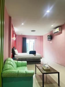 a living room with a green couch and a bed at เอนกายสบายรีสอร์ต in Ban Tha Nang Hom (1)