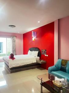 a bedroom with red walls and a bed and a couch at เอนกายสบายรีสอร์ต in Ban Tha Nang Hom (1)