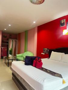 a bedroom with a bed with a red wall at เอนกายสบายรีสอร์ต in Ban Tha Nang Hom (1)