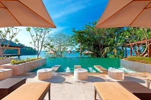 プーケットタウンにあるThe Westin Siray Bay Resort & Spa, Phuketのテーブルとパラソル付きのインフィニティプールを提供しています。