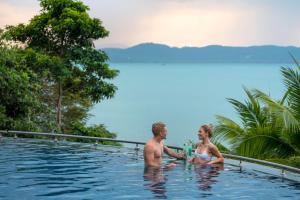 a man and a woman sitting in a swimming pool at The Westin Siray Bay Resort & Spa, Phuket in Phuket Town