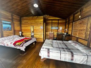 2 camas en una habitación con paredes de madera en Vista Paraíso Lodge, en Barú