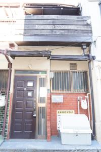 a front door of a brick building with a brown door at リノディア京橋 in Osaka
