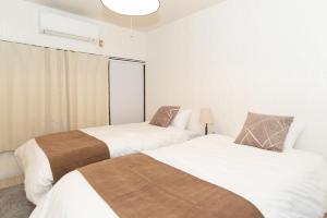 two beds in a room with white walls at リノディア京橋 in Osaka