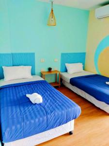 two beds in a room with blue walls at Castaway's 420 in Hua Hin