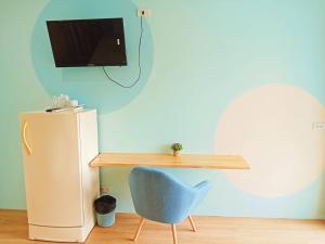 a desk with a blue chair next to a refrigerator at Castaway's hua hin in Hua Hin