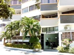 an apartment building with palm trees in front of it at Apartamento en El Rodadero, Santa Marta in Santa Marta