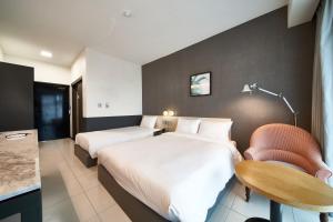 a hotel room with two beds and a chair at Lareem Boutique Hotel in Seogwipo