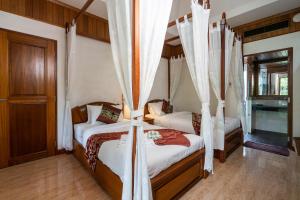 Long Beach Lodge, Chaweng Beach, Koh Samui في شاطئ تشاوينغ: سريرين في غرفة مع ستائر