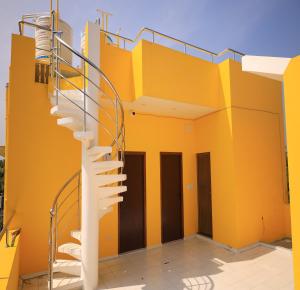 een wenteltrap aan de zijkant van een geel gebouw bij Auro Galaxy Pondy with Swimming Pool in Kottakupam