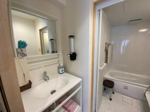 a bathroom with a sink and a mirror and a tub at Guest House Orange no Kaze - Vacation STAY 94759v in Imabari