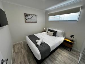 1 dormitorio con 1 cama blanca grande y ventana en Big4 Ulladulla Beachside Holiday Park, en Ulladulla