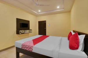 - une chambre avec un lit doté d'oreillers rouges et une télévision dans l'établissement OYO Flagship 13636 Hotel Srinika Grand NEAR Shamshabad Airport, à Shamshabad