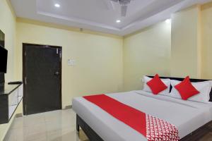 - une chambre avec un lit doté d'oreillers rouges et une télévision dans l'établissement OYO Flagship 13636 Hotel Srinika Grand NEAR Shamshabad Airport, à Shamshabad
