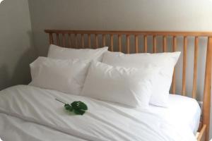 a white bed with white pillows with a green flower on it at Gaon guesthouse in Jeonju