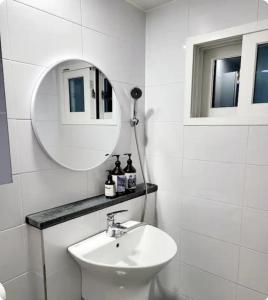 a white bathroom with a sink and a mirror at Gaon guesthouse in Jeonju
